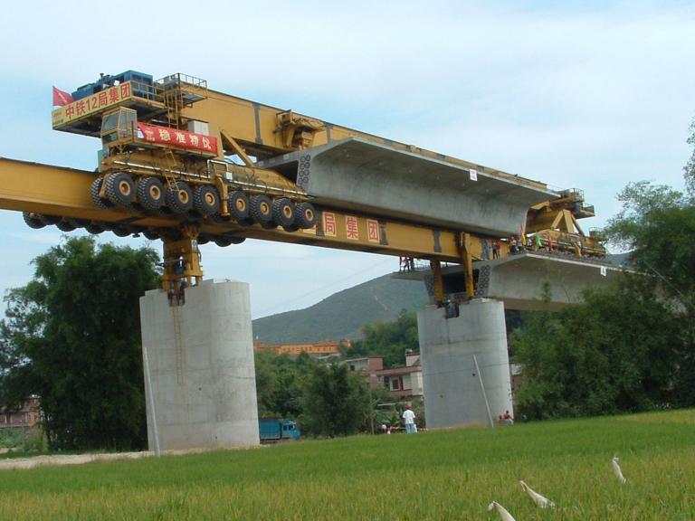 Brückenverlegegerät mit angehängtem Brückensegment steht auf brückenpfeilern über Reisfeld