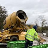 CARMIX befüllt Betonblock Stein Schalungen seitlich vom Gerät mit Beton